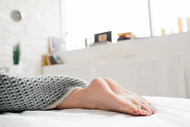 kobieta odpoczywająca w łóżku - stopy