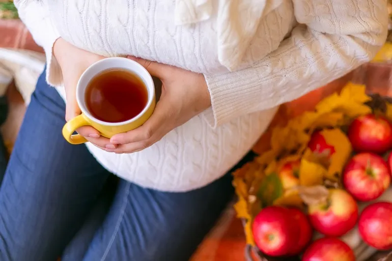 mujer embarazada bebiendo sosteniendo una taza de té